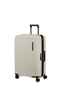 Hartschalenkoffer in hellbeige mit geriffeltem Design, schwarzem Reißverschluss und ausziehbarem Griff. Ausgestattet mit doppelten Rädern für einfache Mobilität.