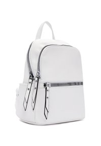 Zaino in pelle bianca con due scomparti con zip, superficie testurizzata, dettagli in zip nera e spallacci regolabili. Design compatto e strutturato.