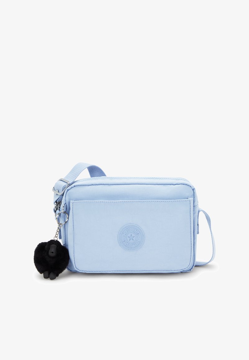 Světle modrá crossbody taška vyrobená z látky s texturovaným povrchem, obsahující přední kapsu, přívěsek opičky a nastavitelné ramínko.