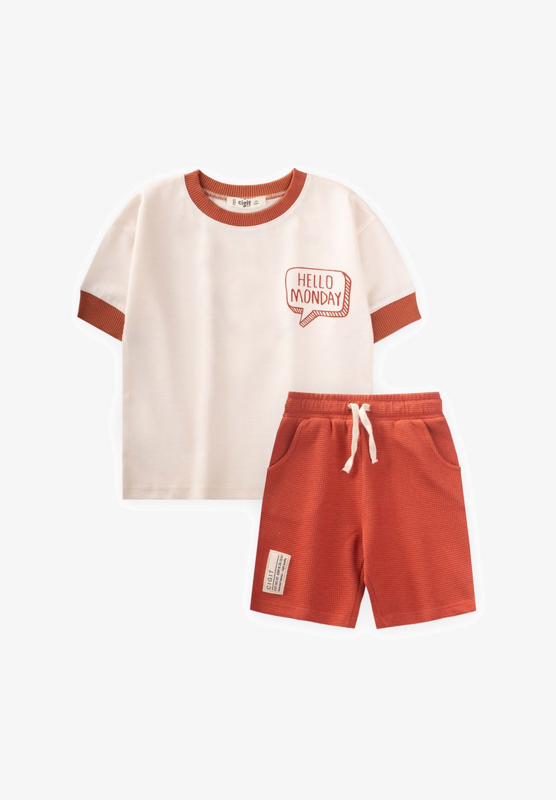 Medvilninis dviejų dalių komplektas, kuriame yra kreminės spalvos trumpomis rankovėmis marškiniai su raudonais akcentais ir grafika „HELLO MONDAY“, derinami su tekstūruotais oranžiniais šortais.