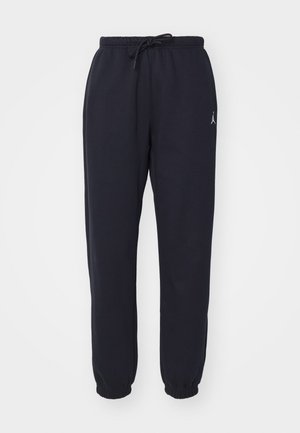Navy jogger-housut pehmeästä kankaasta, jossa on joustava vyötärönauha naruineen, kapenevat lahkeet ja pieni valkoinen logo edessä.