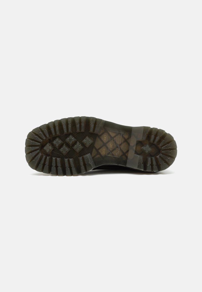 Suela de bota de goma negra con patrón de banda de rodadura profundo, que presenta una combinación de tacos redondeados y angulares para una mayor sujeción y tracción.