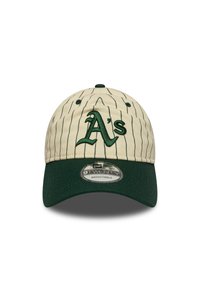Gorra de béisbol beige con acentos verdes, rayas y logotipo bordado de "A's". Correa ajustable en la parte posterior. Diseño de visera plana.