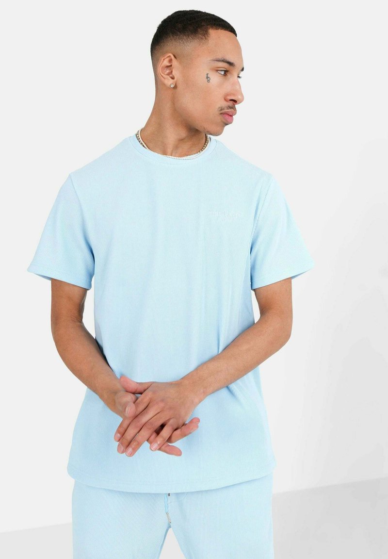 Hele helesinine, ribadega t-särk lühikeste varrukatega ja ümar kaelus. Omab pehmet tekstuuri ja peent logo detaili ees.