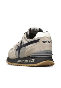 Světlé semišové a šedé síťované tenisky s černou hvězdou na logu, šedými akcenty a texturovanou černou podrážkou s nápisem "JUST SAY WIZZ".