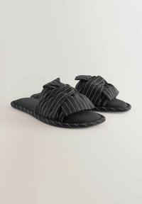 Black slippers with a knotted fabric upper featuring a pinstripe pattern, soft footbed, and open toe design.