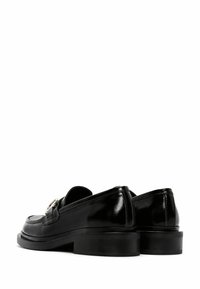 Black patent leather loafers with a low stacked heel, featuring a shiny silver accent on the upper. Smooth, glossy surface and structured design.
