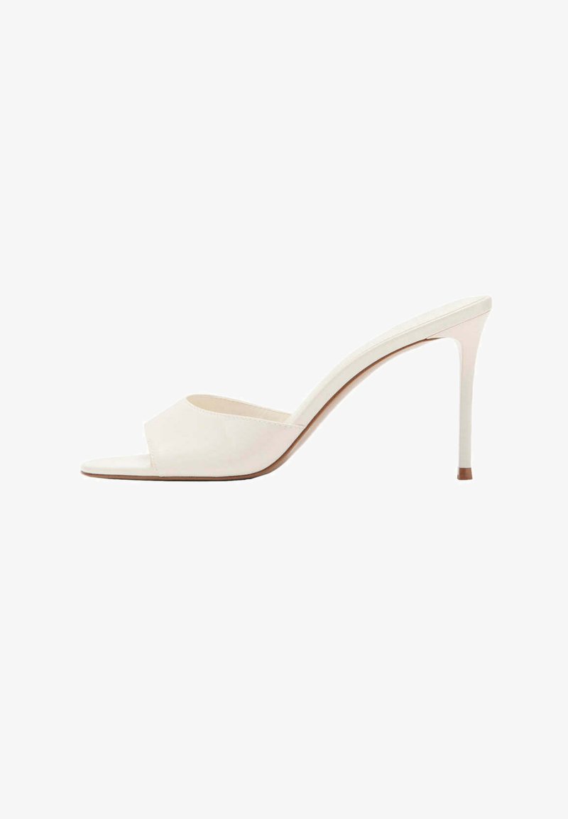 Mule blanche à bout ouvert avec une seule large bride et un talon stiletto fin sur un fond blanc uni.