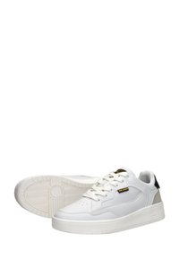 White leather sneakers with mesh panels, flat white laces, and a silver heel accent. Thick rubber sole with patterned tread.
