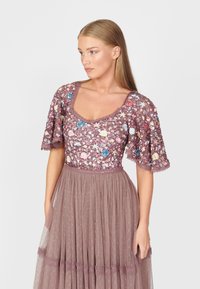 Beaded, kwiecista sukienka w odcieniu mauve z krótkimi, rozkloszowanymi rękawami i teksturowaną tiulową spódnicą. Posiada kwadratowy dekolt i koronkowe wykończenie.