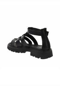 Sandali neri con fasce spesse e suola imbottita. Progettati con una cerniera laterale e battistrada robusto per la trazione.