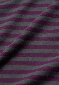 Lila und graue, horizontal gestreifte Stoff mit sanften Falten und sichtbarer Textur in einer Nahaufnahme.