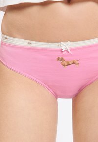 Roze katoenen slipje met een decoratieve witte kantafwerking en een kleine teckelprint aan de voorkant. Voorzien van een decoratief strikje in de taille.