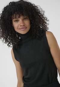 Schwarzes ärmelloses Rollkragenshirt mit weichem, strukturiertem Strick; dezenter Schimmer reflektiert das Licht; figurbetontes Design, das den Körper leicht umschmeichelt.