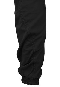 Black, elasticized cuff cargo pants made from a textured fabric, featuring side seams and a relaxed fit.