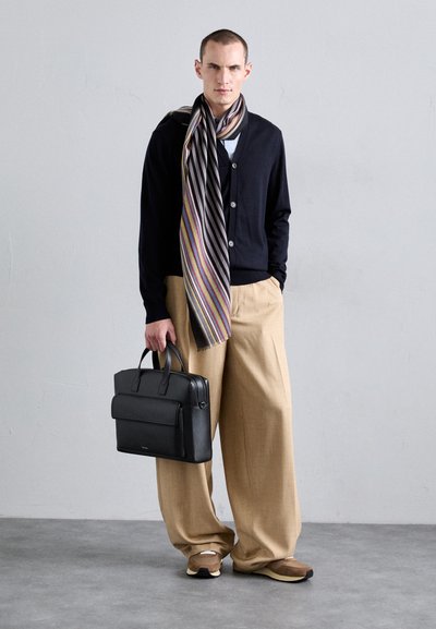 Malette en cuir noir, cardigan bleu marine, écharpe rayée avec des accents violets, pantalon large beige, baskets beiges, design minimaliste.