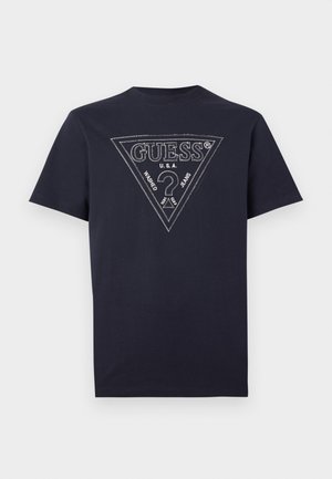 T-shirt noir à manches courtes avec un grand logo triangulaire Guess cousu, comprenant un point d'interrogation et le texte "U.S.A. Washed Jeans" sur le devant.