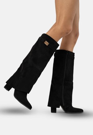Botas altas de ante negro hasta la rodilla con tacón grueso, que cuentan con una cremallera lateral y un acento de puño doblado con un detalle metálico.