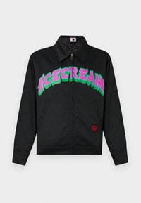 Μαύρο μπουφάν με φερμουάρ, μυτερό γιακά, εμπρόσθιες τσέπες και μεγάλο πολύχρωμο κείμενο «ICECREAM» σε ροζ και πράσινο στο στήθος.