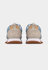 Par blå og beige sneakers med hvide mellemsåler og brune ydersåler vist bagfra på hvid baggrund.