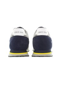 Le scarpe da ginnastica in suede blu e mesh presentano una suola grigia con un accento giallo e il testo "SINCE 1890" sul tallone bianco.
