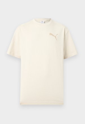 T-shirt crema a maniche corte con logo Puma beige sul petto a sinistra e scollo rotondo, esposta su sfondo chiaro uniforme.