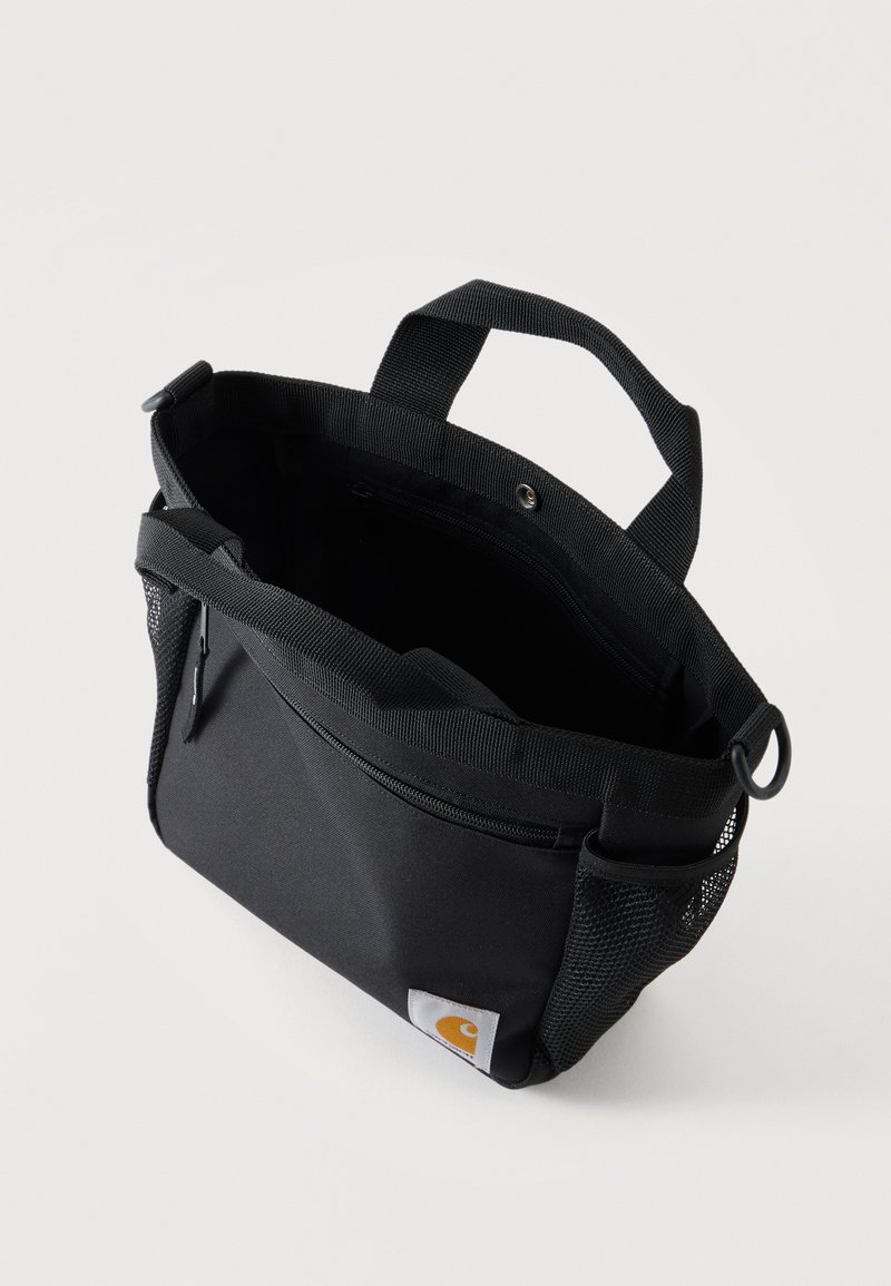 Borsa tote nera con manici, tasca frontale con cerniera, tasche laterali in rete e patch con logo Carhartt nell'angolo inferiore.