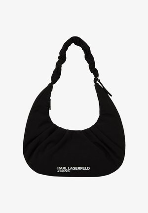 Juoda pusmėnulio formos petnešinė rankinė su paminkštinta rankena ir baltu užrašu „Karl Lagerfeld Jeans“ priekyje.