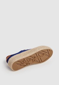 Podešev modré espadrille tenisky s jute střední podrážkou a raženým nápisem "Pepe Jeans" na hnědé gumové podrážce, na bílém pozadí.