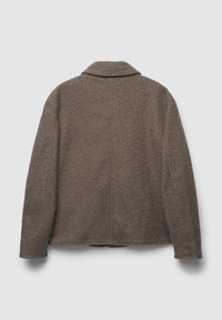 Giacca in pile marrone con texture appesa con il retro rivolto in avanti su uno sfondo chiaro e uniforme.