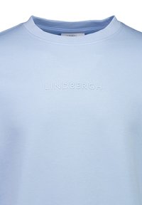 Ljusblå t-shirt av mjukt tyg, med rundad halsringning och upphöjd "LINDHBERGH"-text på framsidan, minimalistisk design.