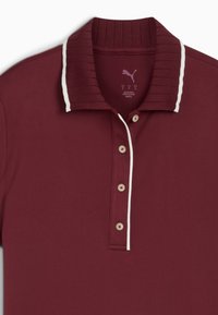 Burgundy polo-paita, jossa on uurrettu kaulus, valkoiset koristeviivat ja viisi napin reikää. Valmistettu sileästä ja hengittävästä kankaasta.