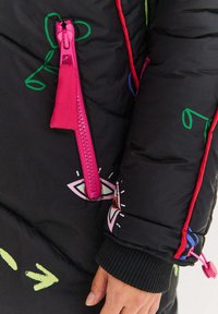 Černá prošívaná bunda s růžovým zipem, vícebarevnými grafickými prvky, elastickými manžetami a ozdobným prošitím na texturovaném povrchu.