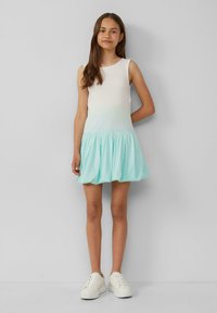 Robe sans manches avec un haut blanc se fondant en une jupe évasée vert menthe. Fabriquée en tissu doux ; design simple avec un col rond.