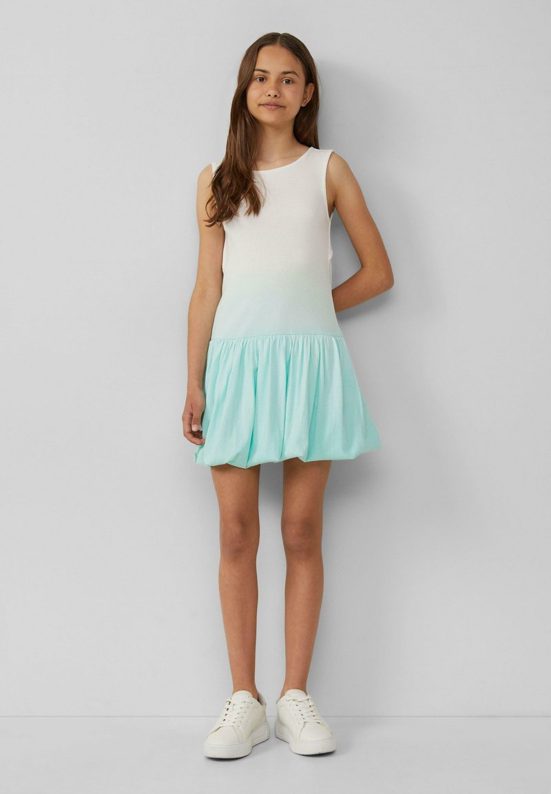 Robe sans manches avec un haut blanc se fondant en une jupe évasée vert menthe. Fabriquée en tissu doux ; design simple avec un col rond.