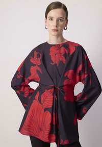Musthave tumeda punaste lilledega, mille talje on kinni seotud paelaga. Omab pikki varrukaid ja ümarat kaelust. Sile tekstuur.