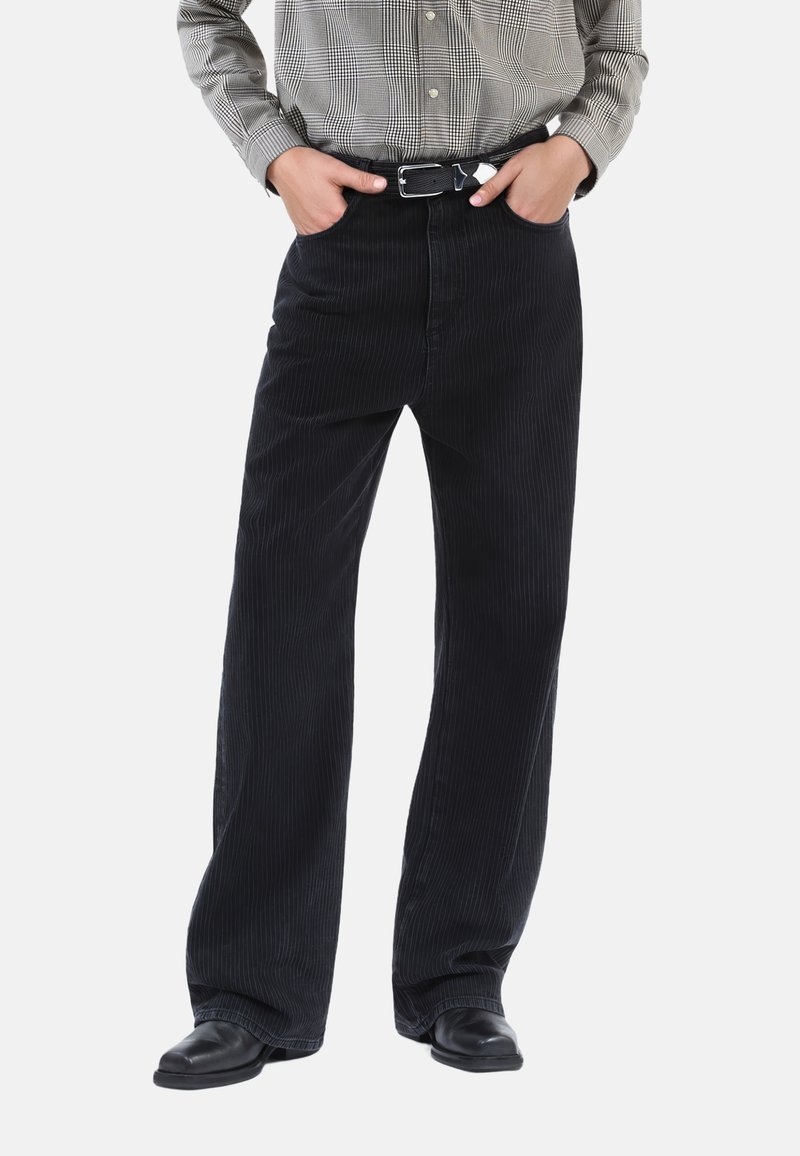 Sorte kordbukser med bred pasform, der har lodrettestriber og en mid-rise talje, parret med en grå ternet skjorte.