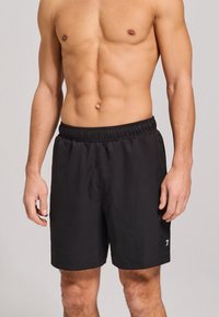 Schwarze Badehosen mit einem elastischen Bund, glattem Stoff, knielanger Schnitt und einem kleinen Logo am linken Bein.