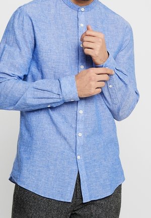 Camicia azzurro chiaro con colletto alla coreana, tessuto strutturato e maniche lunghe, con bottoni bianchi e orlo curvo.