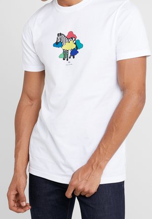 Man draagt een wit t-shirt met een zebra-illustratie, omringd door kleurrijke wolkvormen in blauw, rood, geel, groen en teal.