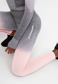 Grå och rosa gradientträningsleggings med ribbad textur och "SQUATPROOF"-märkning, tillsammans med en matchande långärmad topp.