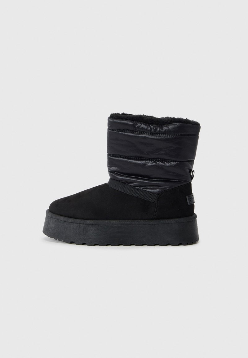 Bottines noires avec une partie inférieure en daim et une partie supérieure rembourrée et brillante. Présente une épaisse semelle noire et un poignet texturé pour l'isolation.