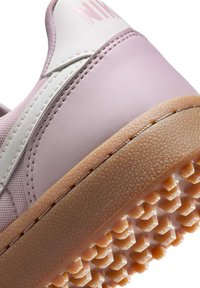 Ljust rosa sneakers med vita accenter. Texturerad gummisula med diamantmönster. Slät översida med sydda detaljer.