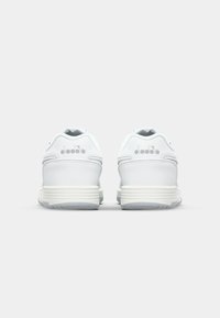 White athletic shoes with a smooth leather finish, padded collar, and textured rubber sole. Subtle logo detail on the heel.