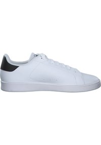Zapatilla de cuero sintético blanca con una superficie lisa, puntera redonda y un acento negro en el talón. Presenta seis ojales y una suela de goma plana.