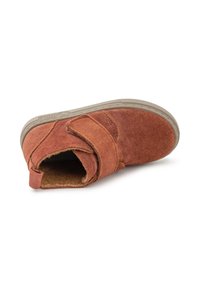 Botín de ante marrón con una correa de Velcro, punta redonda y suela de goma texturizada color marrón claro. Interior forrado con material suave para mayor comodidad.