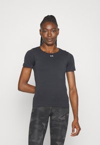 Tricou sport negru cu maneci scurte, guler rotund și logo pe piept; textură netedă. Asortat cu colanți negri cu un model.