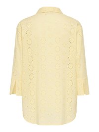 Svijetložuta bluza dugih rukava s cvjetnim izrezima u obliku otvora za oči i klasičnim ovratnikom, prikazana s leđa.