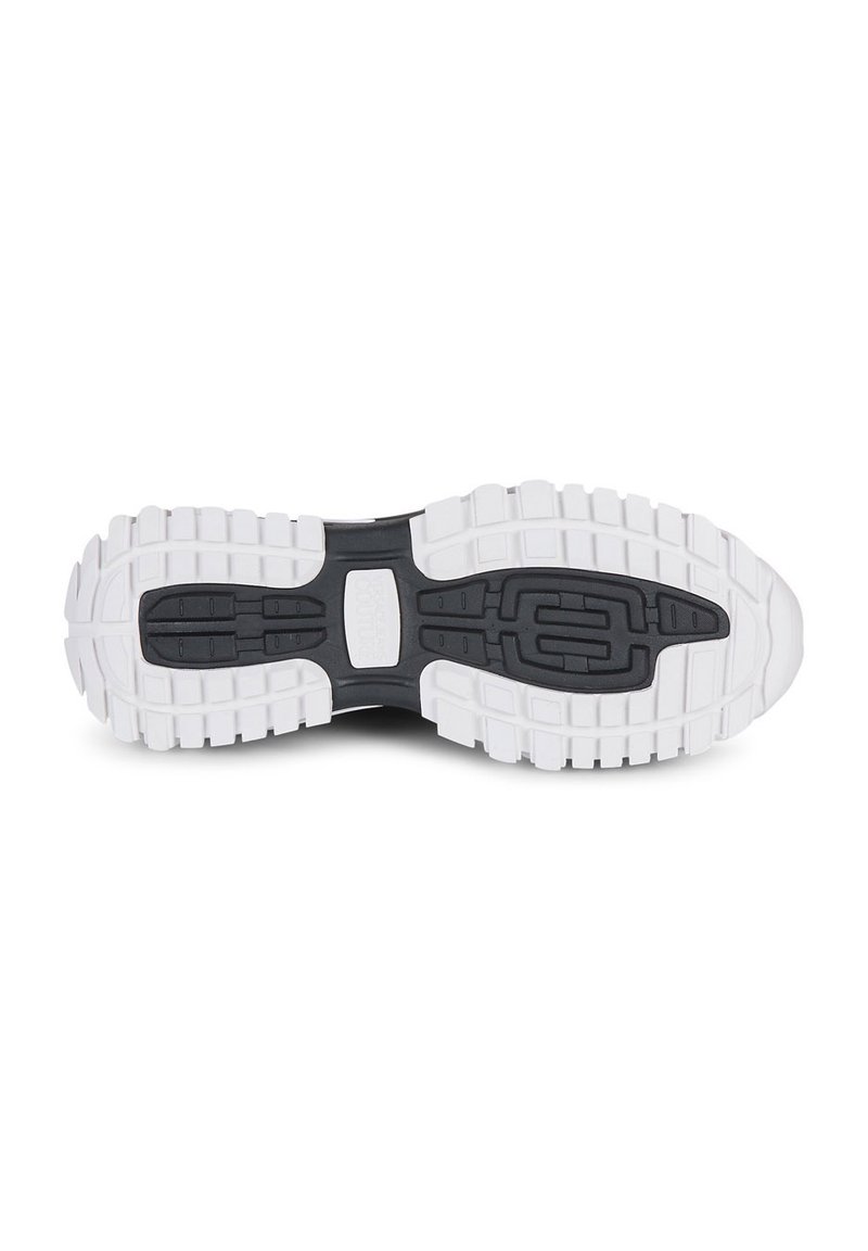 Suela de zapatilla deportiva en blanco y negro que presenta un diseño de goma texturizada y con patrones, con surcos profundos para un buen agarre y flexibilidad.