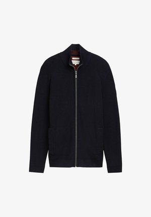 Cardigan cu fermoar de culoare bleumarin, cu manșete și tiv ondulat, având buzunare laterale și guler înalt. Textură moale, conceput pentru căldură și confort.